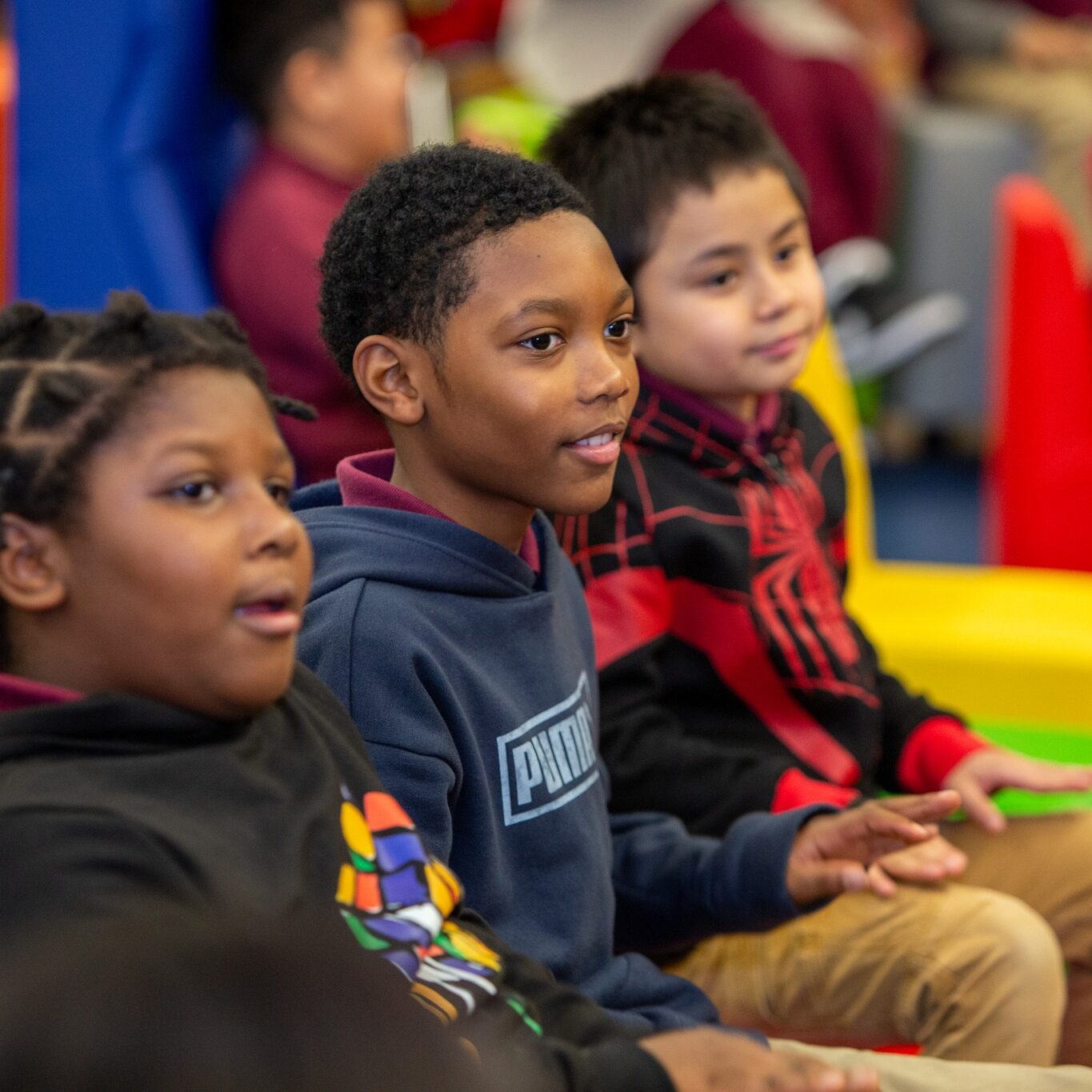 Three students sit together in a bright, colorful classroom at Stephen Girard Elementary School